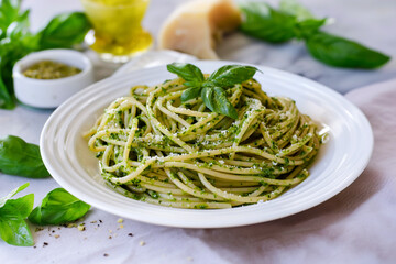 tasty italian spaghetti pasta alla genovese with green pesto sauce, cheese and basil, close up