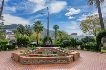 Ornate fountains inlaid with traditional mosaics in the Chefchaouen Park with the Rif Mountains as a backdrop. Tranquil atmosphere, Morocco. © twabian