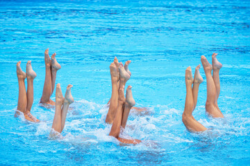 Artistic swimming team performing synchronized legs movement in swimming pool