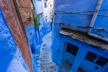 Under clear skies, the Chefchaouen alleys are a labyrinth of walls and staircases in varying shades of blue. Chefchaouen, Morocco.