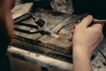 Close-up of a hand of a goldsmith who builds a precious jewel with valuable diamonds. To make the...