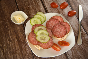 2 rolls with salami on a plate with tomatoes