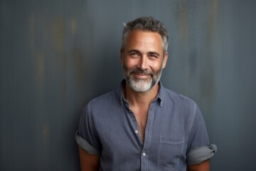 Obraz premium Portrait of a grinning man in his 50s wearing a comfy flannel shirt isolated in bare concrete or plaster wall