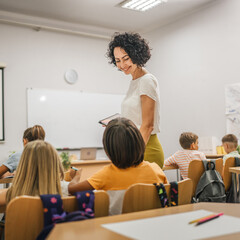 Mature teacher hold tablet and check how her students learn lesson