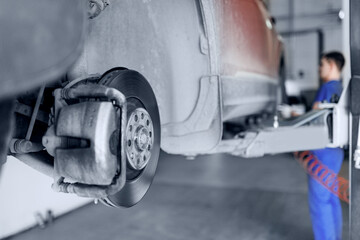 Fototapeta premium Closeup of steel brake disc in car service. Concept for replacing wheel pads in garage.