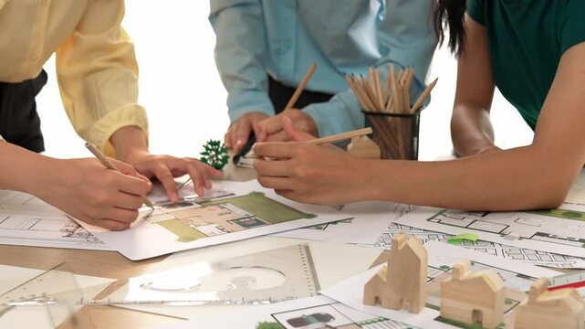 Smart architect and safety engineer discussion about building blueprint on table with architectural document, measurement tools and wooden block scatter around at modern office. Closeup. Delineation.