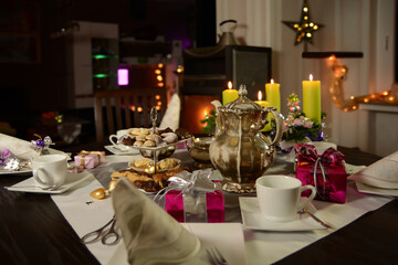 Coffee table set for Christmas. Silver coffee pot, Advent wreath, different home baked christmas cookies on an etagere and small gifts on the table.