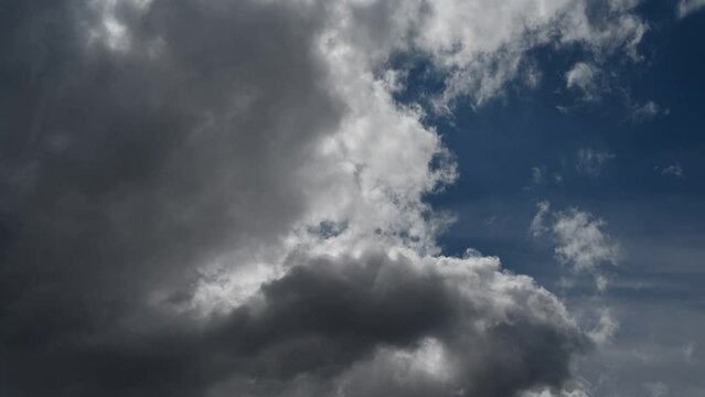 A time lapse that is looking up at building storm clouds in a partly blue sky. The pending storm creates a moody atmosphere.  
