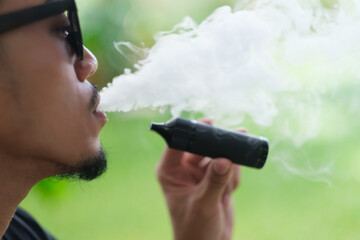Vaping with an electronic cigarette vape device concept. Smoking with an E-cigarette blowing smoke...