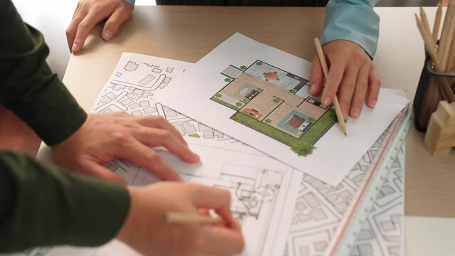 Professional engineer team discussion about house design on meeting table with architectural equipment and building blueprint scatter around at modern office. Focus on hand. Closeup. Delineation.