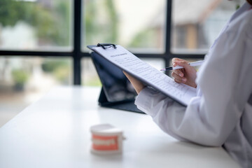 A woman is sitting at a desk with a clipboard and pen
