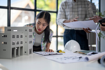 A woman is looking at a model of a building while two men look on