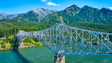 Aerial View of Steel Truss Bridge Over River in Lush Forested Mountains