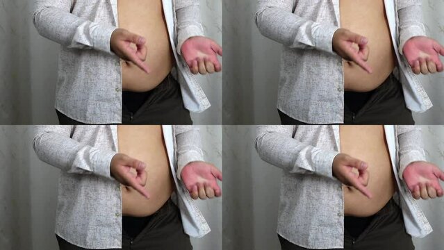 unrecognizable Male, overweight. fat man with bare fat belly shakes folds on stomach. no face. Obese man shake, spat and rub belly fat belly. Abdomen muscles jiggle. side view. isolated on white wall