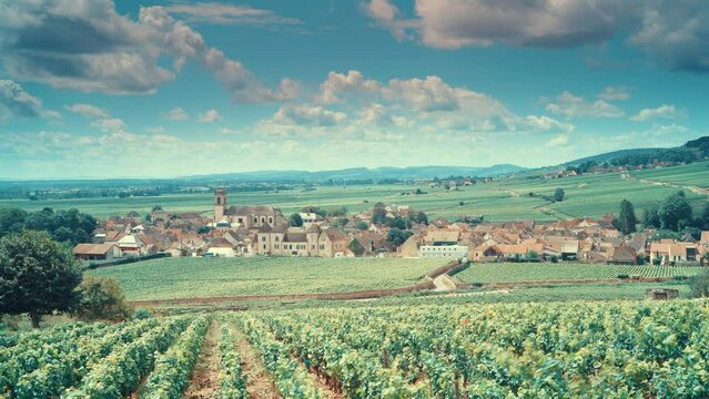 Time lapse of clouds moving over summer vineyards landscape and village Pommard. Burgundy road. Cote de Beaune, Cote d'Or, France.


