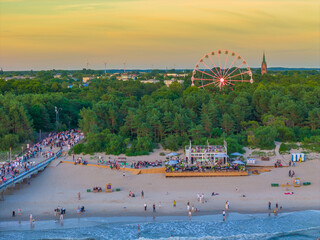 Ferris wheel in the city next to the beach among the trees in the evening. Aerial drone sunset...