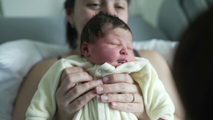 Mother joyfully holding her newborn baby close at hospital. mother’s proud smile and the baby’s content expression capture a tender moment 