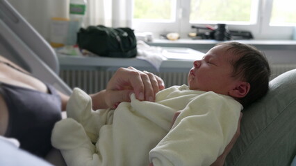 Obraz premium Newborn baby peacefully resting on mother’s lap in hospital bed. serene expression on the baby's face and the comforting embrace of the mother highlight the warmth and security of their bond