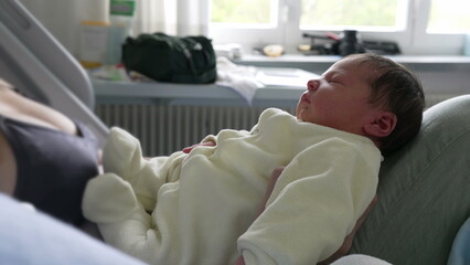 Newborn baby peacefully resting on mother’s lap in hospital bed. serene expression on the baby's...