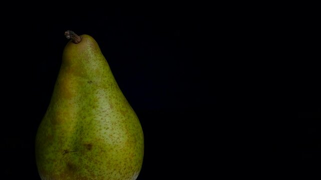 a green pear on a dark background