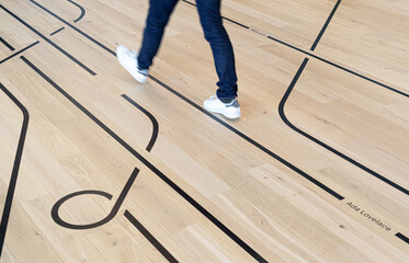 "Office Corridor: Wooden Floor with Vinyl Directional Lines and Walking Person"