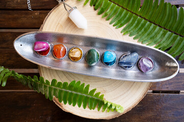 seven chakras stones over wooden background, energy healing concept