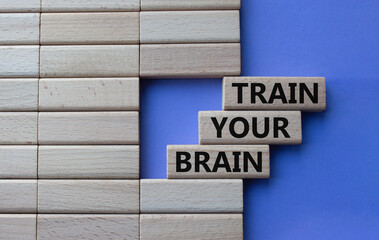 Obraz premium Train Your Brain symbol. Concept words Train Your Brain on wooden blocks. Beautiful purple background. Businessman hand. Business and Train Your Brain concept. Copy space.