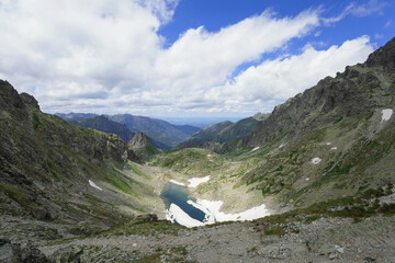 Bielovodska dolina and Zamrznute pleso, View from Polsky hreben, High Tatras, Vysoke Tatry, Slovakia. Landscape with rocks and mountain covered by ice. Cloudy summer weather. Wide angle.