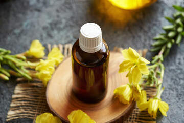 Evening primrose oil in a dark glass bottle with fresh Oenothera biennis flowers
