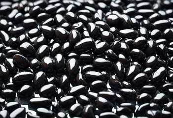 Fototapeta premium A glossy pile of black beans reflecting light showcasing their smooth texture and rich color perfect
