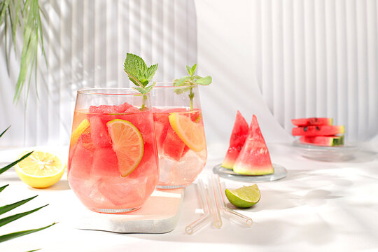 Ice cold homemade lemonade or cocktail with mint, watermelon and fruit, a recipe for a refreshing summer drink. Two glasses with fruit drink on sunny table, detox diet and weight loss concept, 