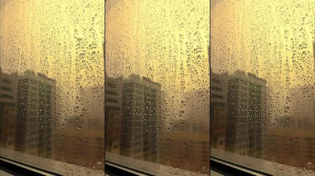 Rain falling on window in skyscraper apartment. Dark and stormy rainy day in big city life. View of dreary Hong Kong cityscape whilst rain drops fall on the window. Abstract somber moody background