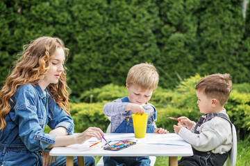 Babysitter and kids enjoying outdoor painting.