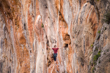 A man walks on a tightrope over an abyss.