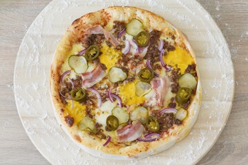 Whole Homemade Pizza with Bacon and Meat on Wooden Table with Ingredients Background. National Pizza Day, La Giornata Mondiale della Pizza, World Pizza Day. Tasty, Food, Fast Food, Hunger.