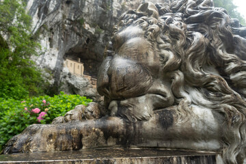 Entrance to the Covadonga cave and hermitage, framed by lush greenery and a lion statue in Asturias, Spain