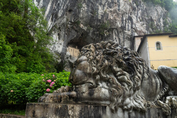 Entrance to the Covadonga cave and hermitage, framed by lush greenery and a lion statue in Asturias, Spain