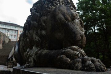 Entrance to the Covadonga cave and hermitage, framed by lush greenery and a lion statue in Asturias, Spain