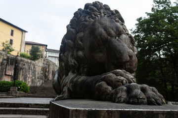 Entrance to the Covadonga cave and hermitage, framed by lush greenery and a lion statue in Asturias, Spain