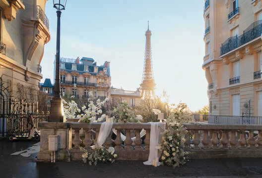 cosy Paris street with view on the famous Eiffel Tower on spring day with white flowers decorations, Paris France