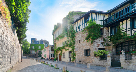 Fototapeta premium View of historical street in quarter Montmartre in Paris, France. Cozy cityscape of Paris with Sacre Coeur church. Architecture and landmarks of Paris