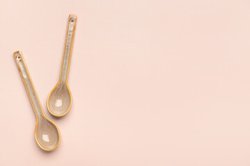 Two ceramic spoons on beige background.Top view