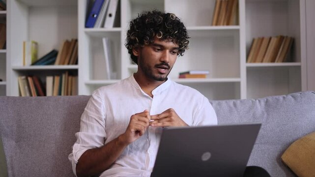 Sad young indian man talk with psychotherapist at online distance remote counselling session indoors Depressed male discussing problem with psychological support by laptop computer at home