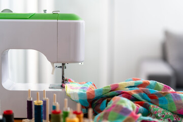 A sewing machine with colorful fabric being stitched, surrounded by vibrant spools of thread....