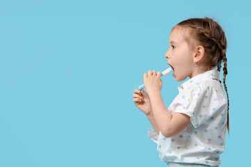 Happy cute little girl with toothbrush on blue background