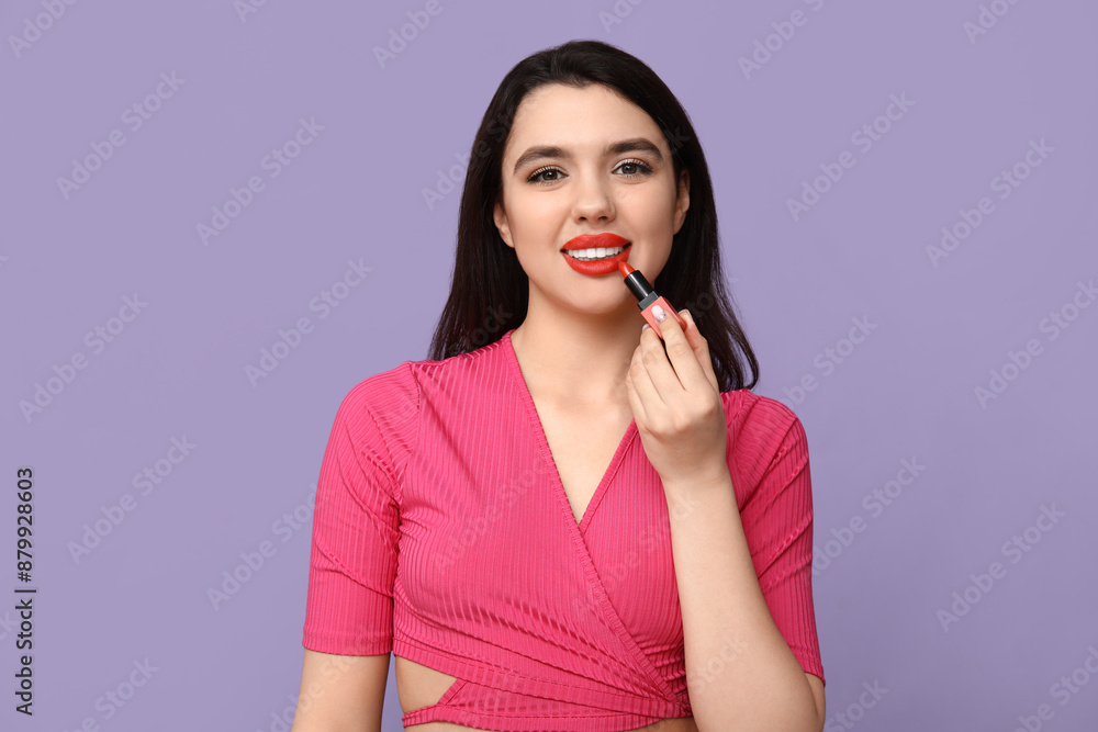 Canvas Prints beautiful young woman applying lipstick on lilac background