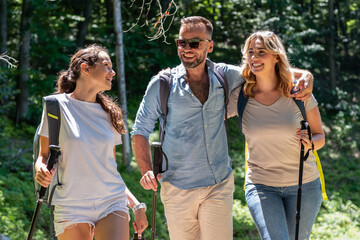 A family enjoys hiking together in nature on a sunny summer day. They walk along a trail, taking in the beautiful surroundings and sharing smiles and laughter.