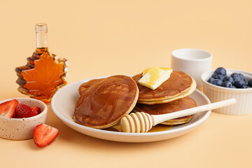 Tasty pancakes with honey and butter on orange background