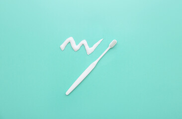 Toothbrush with sample of toothpaste on turquoise background