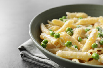 Delicious pasta with green peas and cheese on grey table, closeup